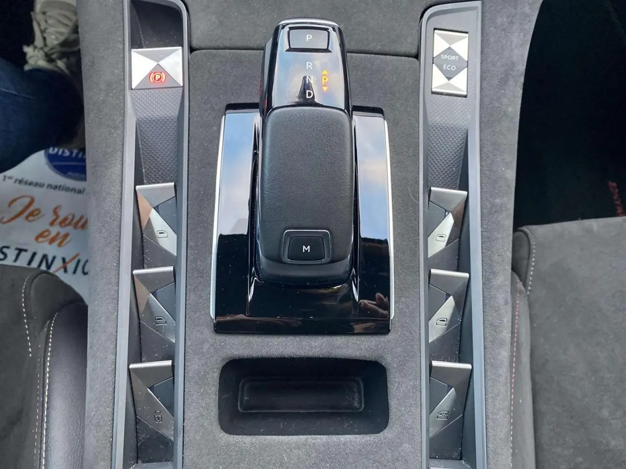 Le levier de vitesses automatique noir au centre de la console centrale grise du DS7 Crossback blanc, avec boutons triangulaires argentés.