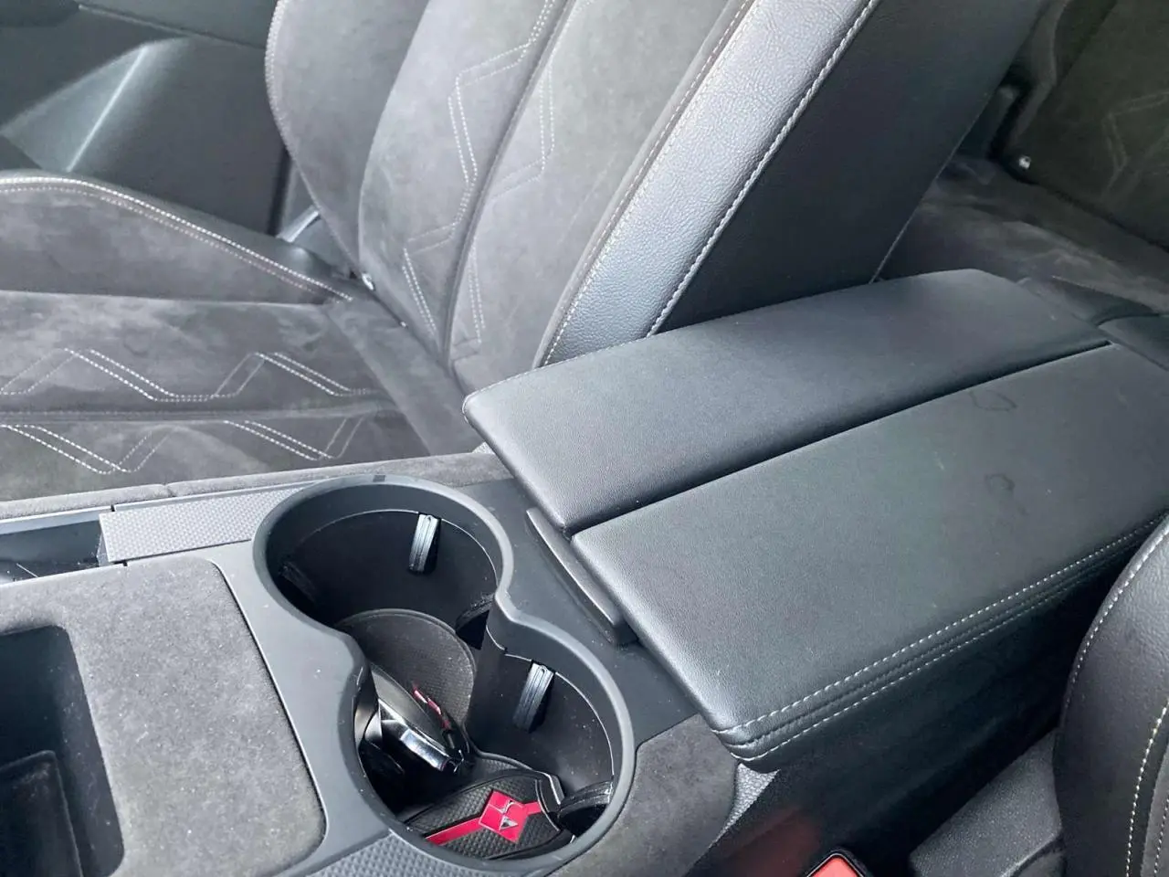 Gros plan sur l'accoudoir central noir et les sièges en alcantara gris du DS7 Crossback blanc 2022 Performance Line.