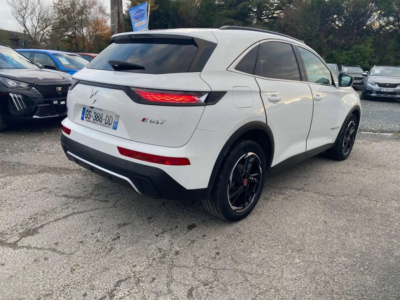 Vue 3/4 arrière droite du SUV blanc DS7 Crossback 2022 avec feux arrière allumés et jantes noires.
