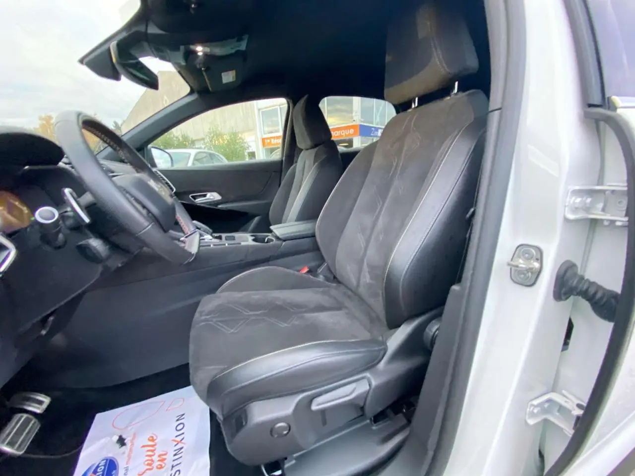 Vue intérieure côté conducteur du DS7 Crossback blanc 2022 avec sièges en cuir noir et alcantara.