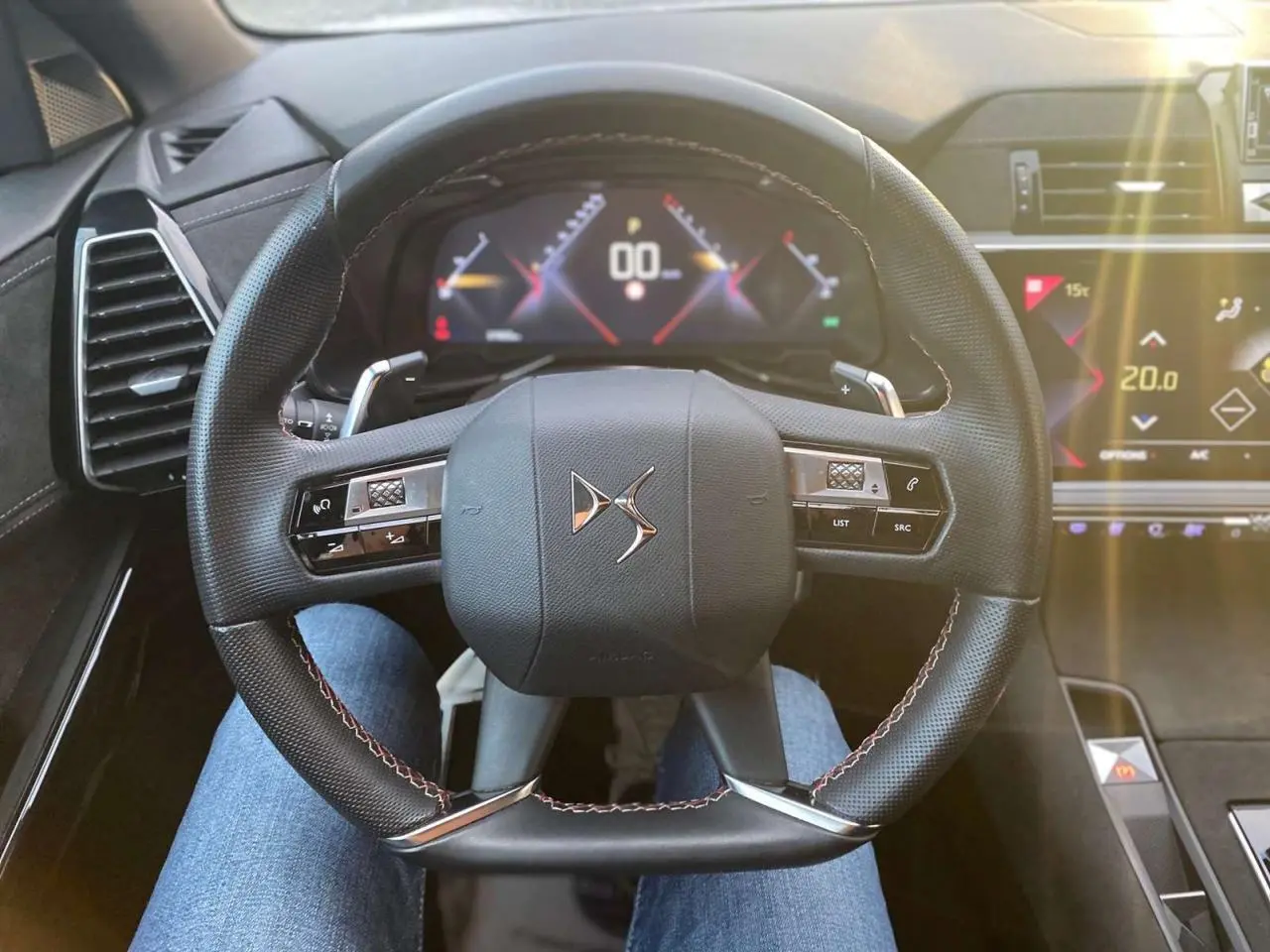 Vue rapprochée du volant DS du DS7 Crossback 2022, avec commandes intégrées et tableau de bord digital lumineux.