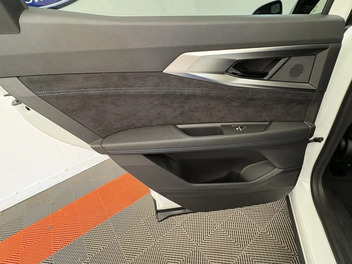 Vue latérale du panneau de porte avant gauche blanc du Renault Espace esprit Alpine avec garniture noire et surpiqûres bleues.