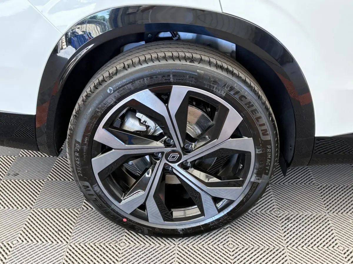 Gros plan sur la roue avant droite du Renault Espace blanc esprit Alpine avec jante alliage noire et argentée.