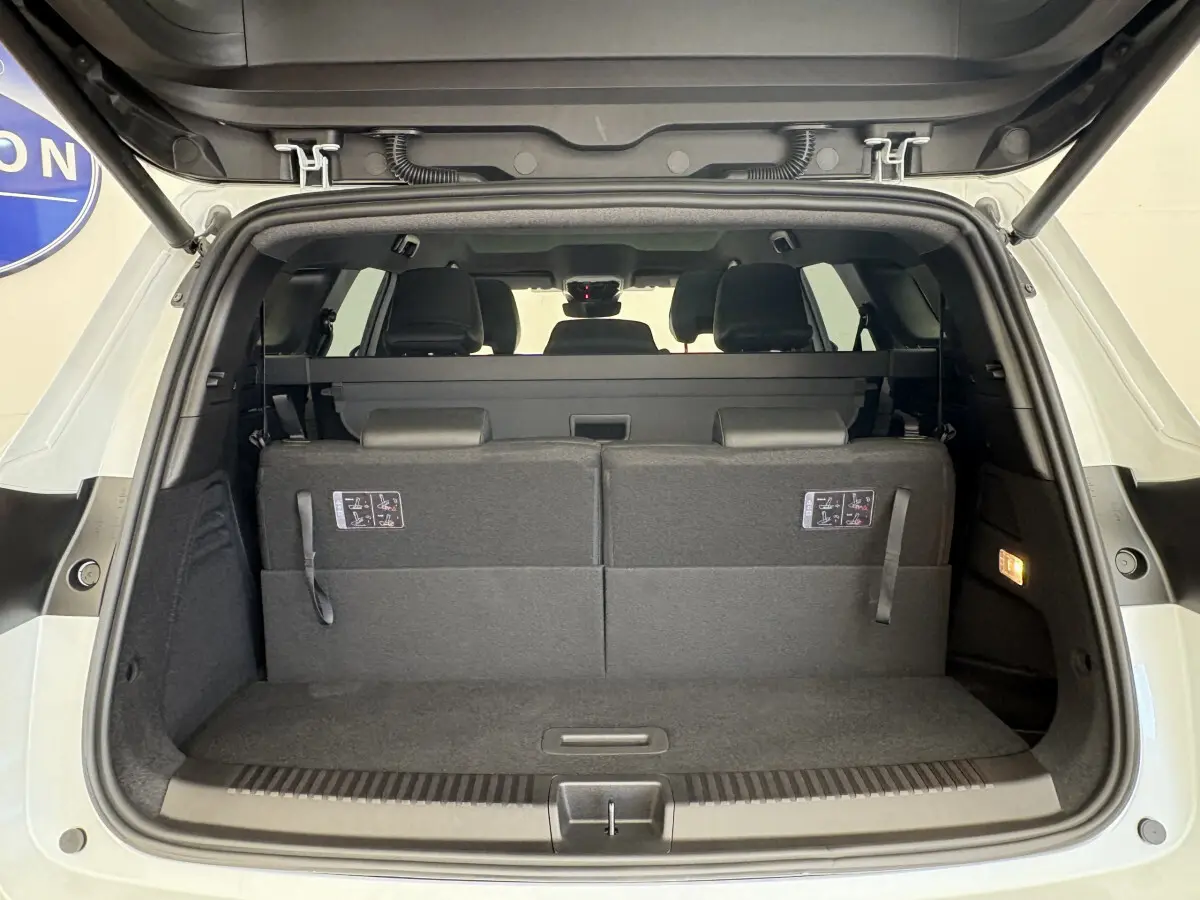 Coffre ouvert vue arrière d’un Renault Espace blanc avec sièges rabattus et banquette arrière visible.