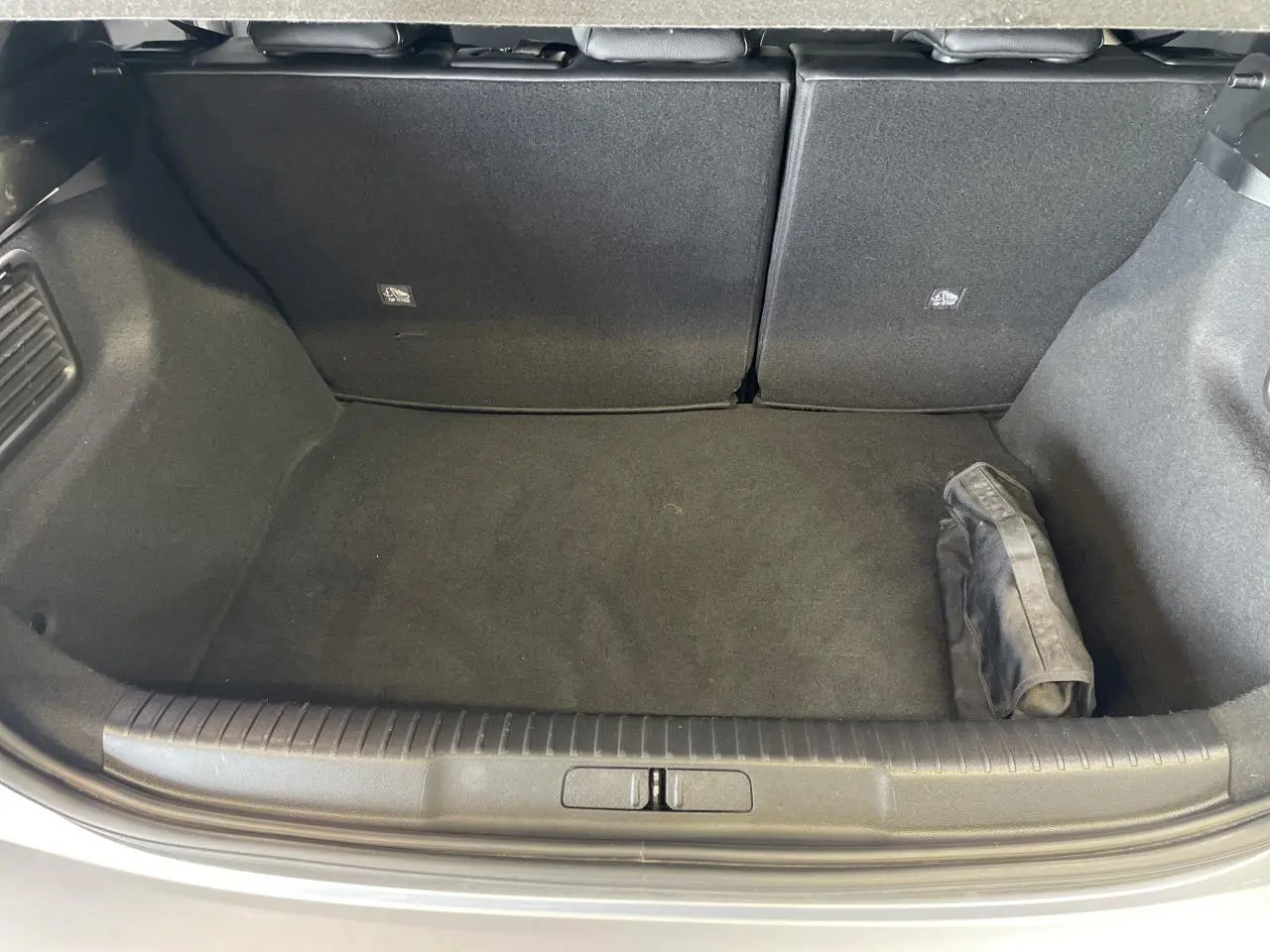 Coffre ouvert vu de dessus d'un DS3 Crossback gris Artense, avec tapis noir et pochette rangée à droite.