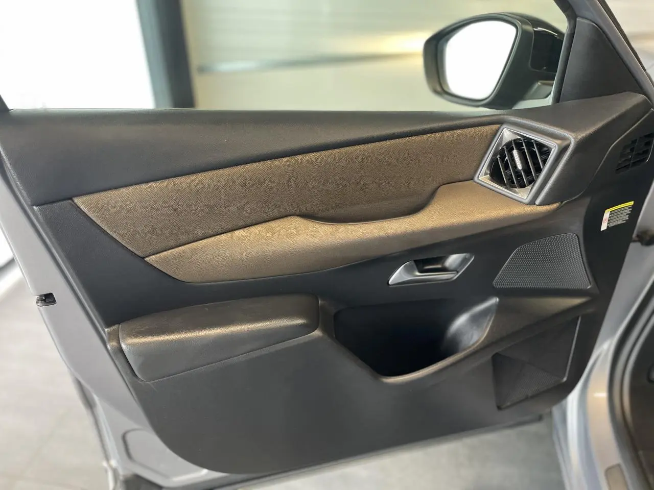 Vue rapprochée de la porte avant droite du DS3 Crossback gris Artense avec garniture noire et commande de vitre.