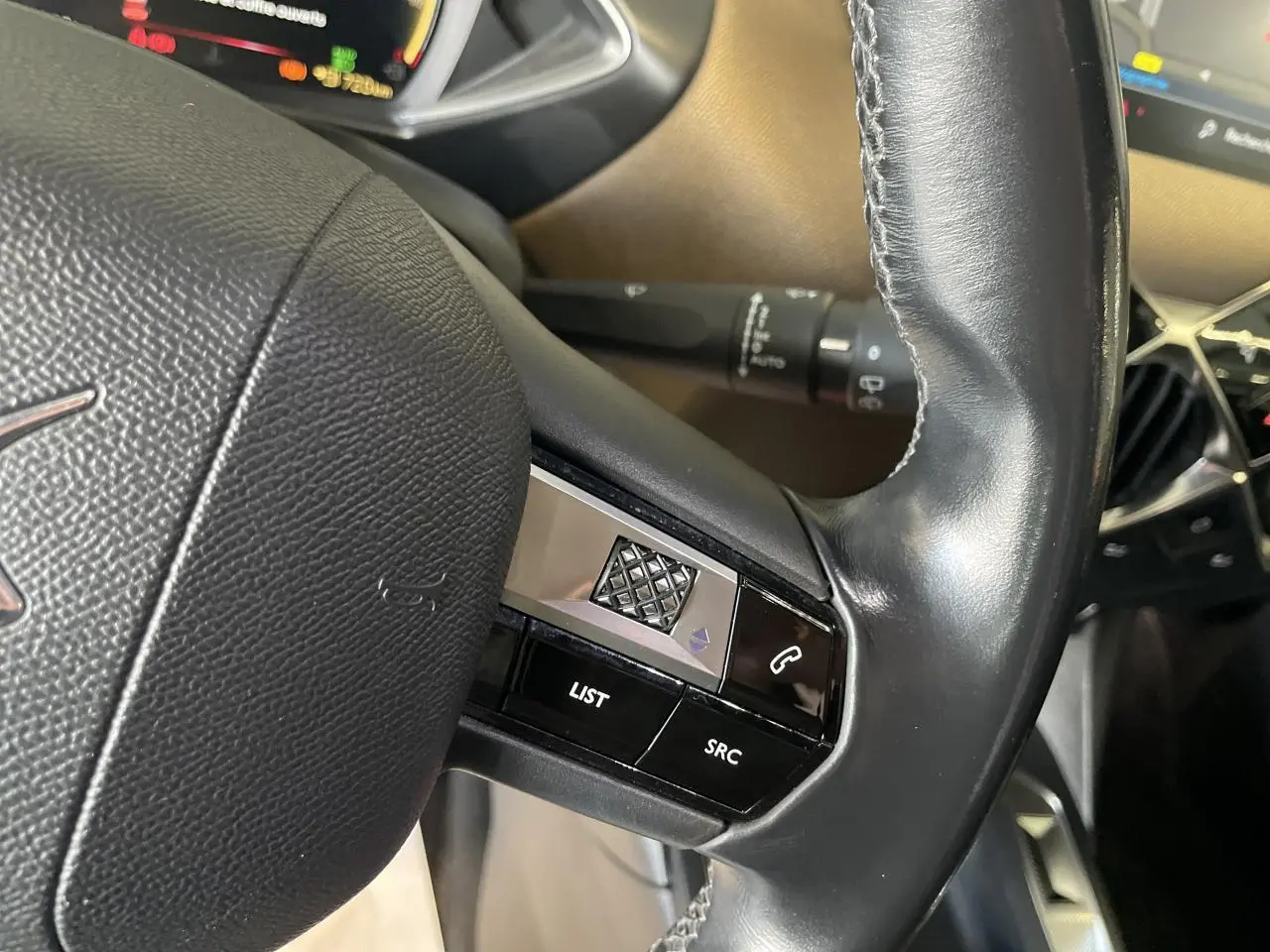 Gros plan sur le volant en cuir noir du DS3 Crossback 1.5 BlueHDi avec commandes intégrées côté gauche.