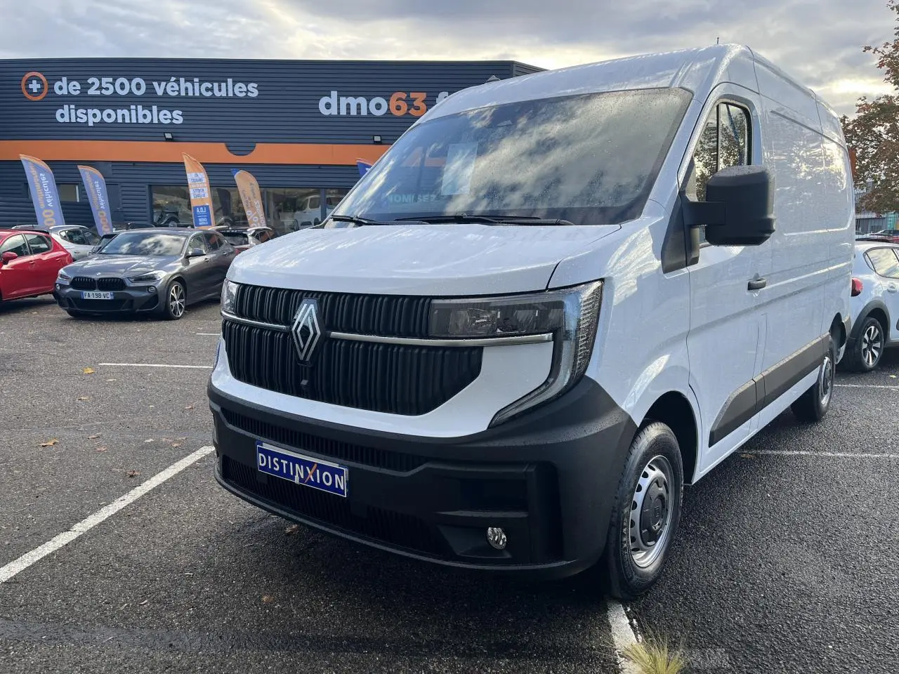 Renault Master blanc en 3/4 avant droit, avec calandre noire verticale et pare-chocs noir mat, stationné en extérieur.