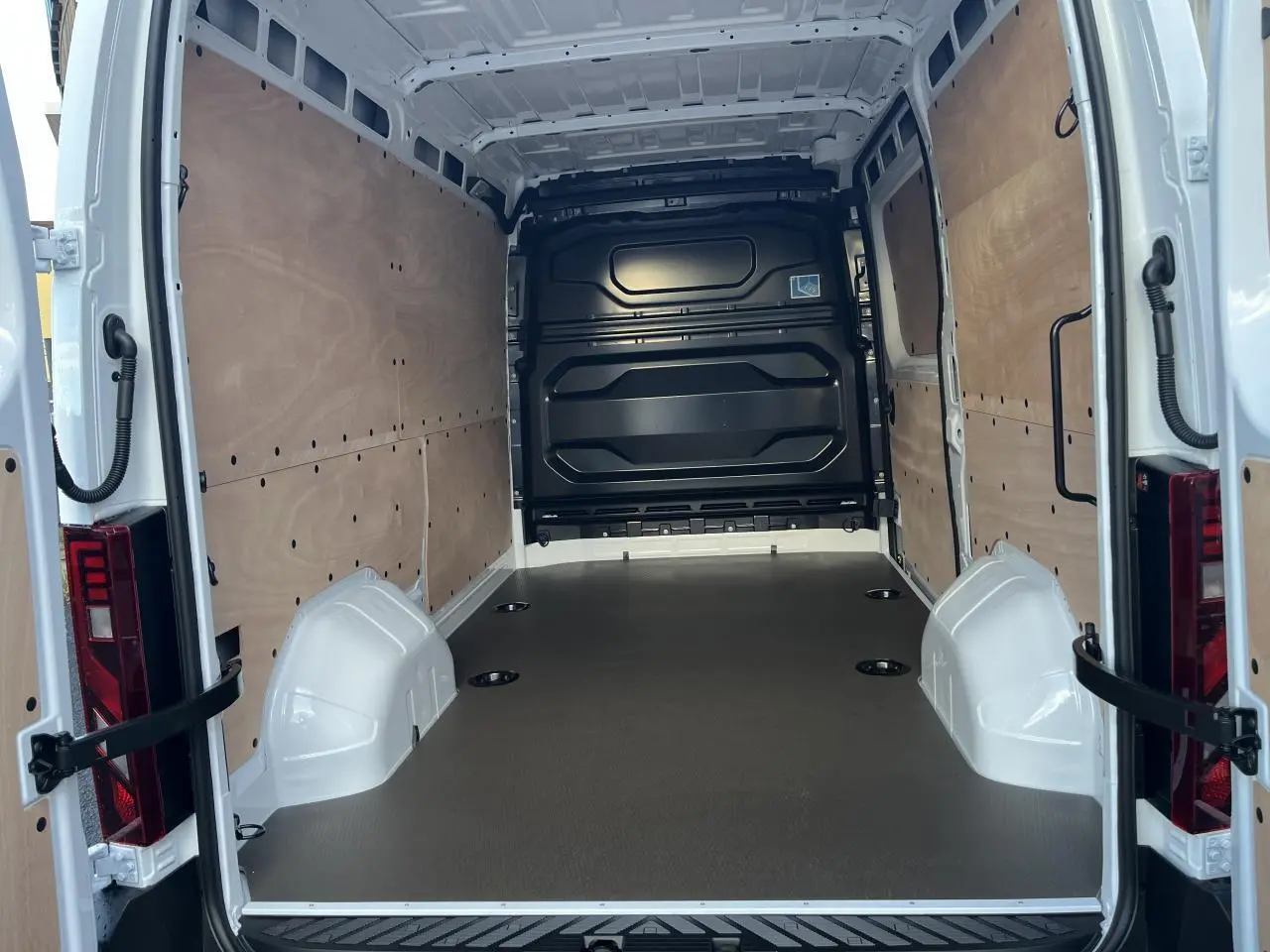 Vue arrière intérieure du Renault Master blanc 2025, montrant l'espace de chargement avec plancher bois et parois latérales tôlées.