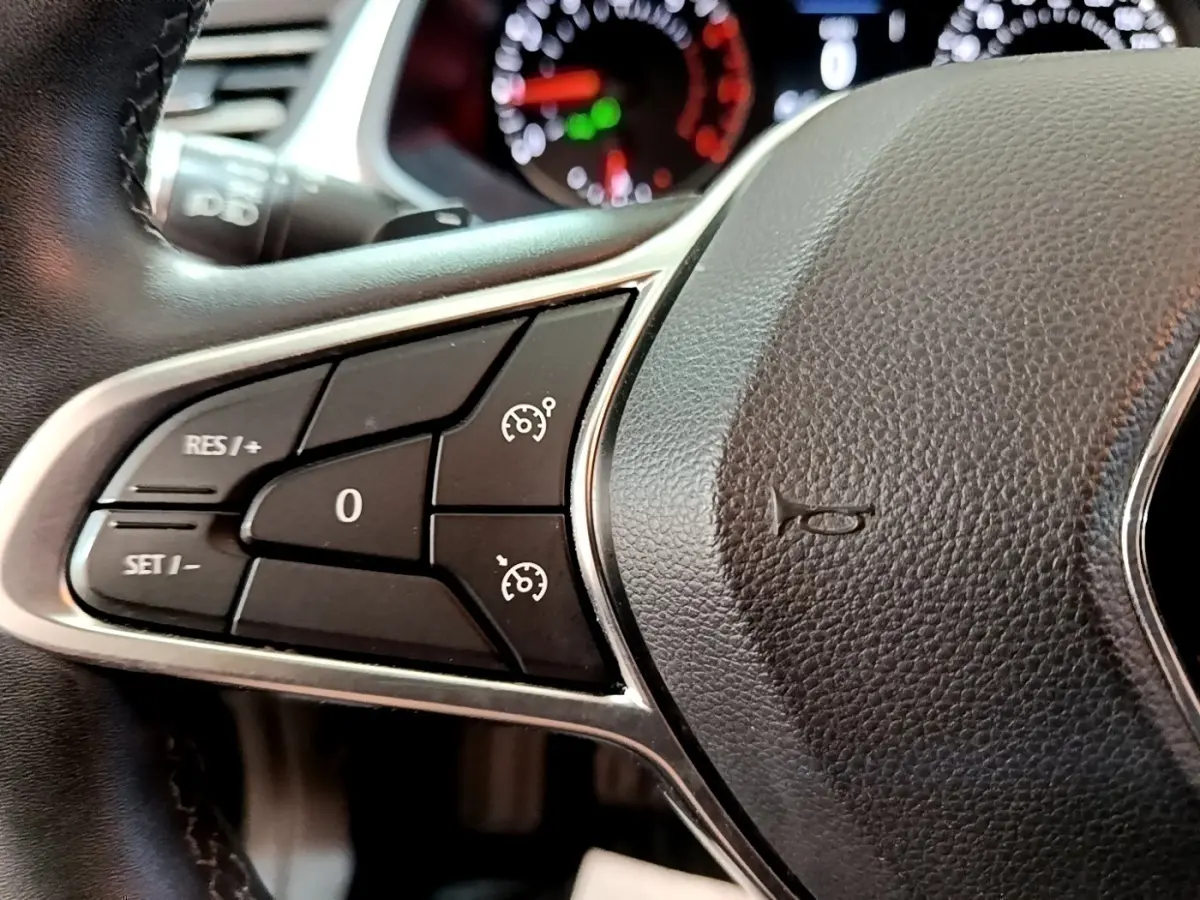 Gros plan sur les commandes du régulateur de vitesse à gauche du volant noir du Renault Captur Business 2021.