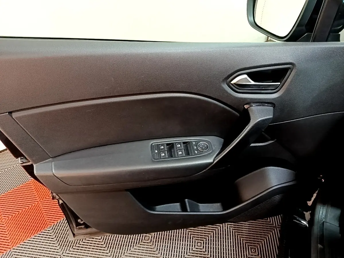 Vue intérieure côté gauche de la porte avant noire du Renault Captur Business avec commandes des vitres et poignée intégrée.