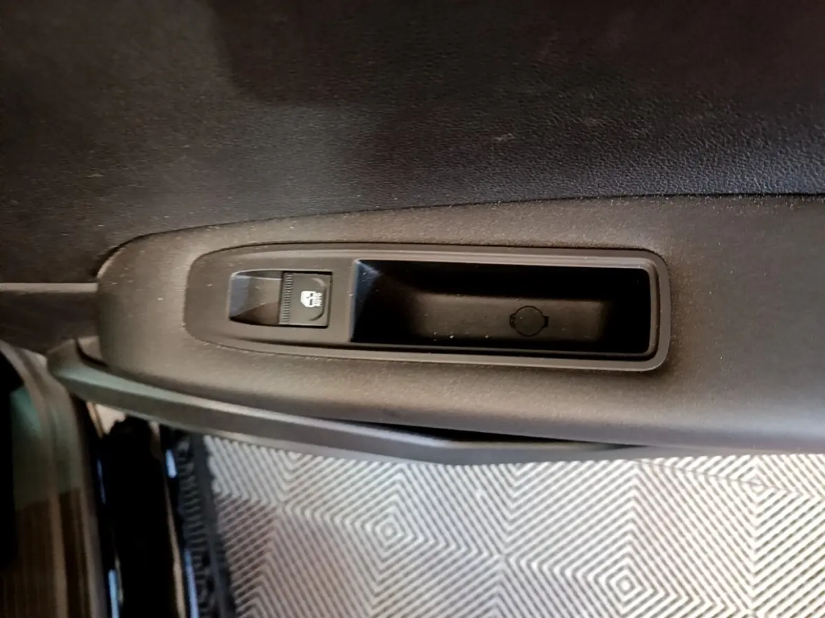 Gros plan sur la poignée intérieure de porte côté gauche du Renault Captur Business noir, avec bouton de verrouillage intégré.