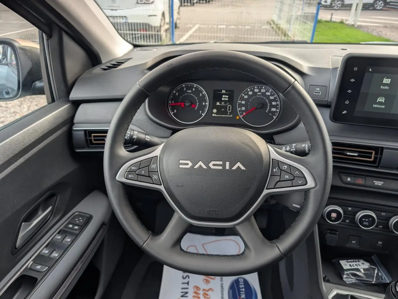 Vue intérieure centrée sur le volant noir DACIA avec tableau de bord et écran tactile du Dacia Jogger Gris métallisé 2025.