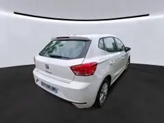 Vue 3/4 arrière droite d'une SEAT Ibiza blanche 2023 avec feux arrière LED dans un studio lumineux.