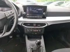 Intérieur de la SEAT Ibiza 2023 blanc, vue du tableau de bord avec écran tactile et levier de vitesse manuel.