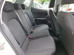 Intérieur arrière de la SEAT Ibiza blanche 2023, sièges tissu gris et ceintures de sécurité visibles côté droit.