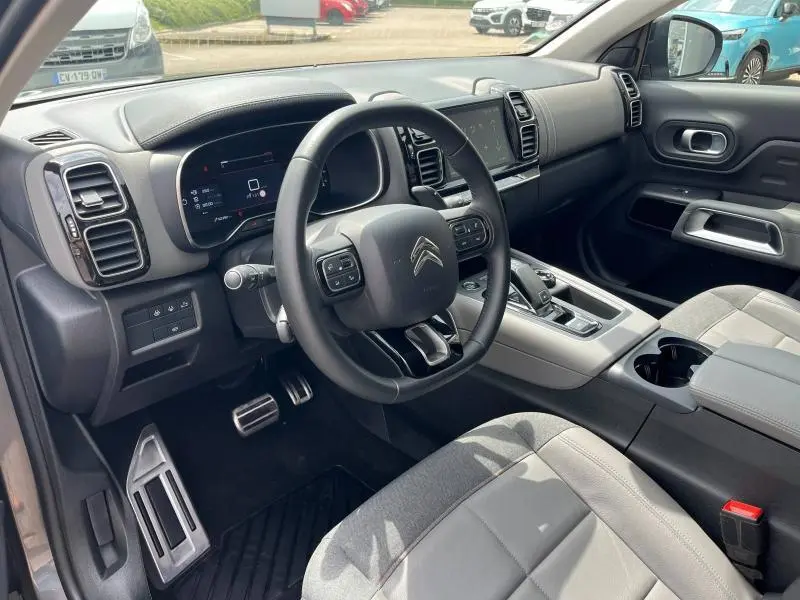 Intérieur côté conducteur du Citroën C5 Aircross 2021, volant cuir noir et sièges gris clair en tissu et alcantara.