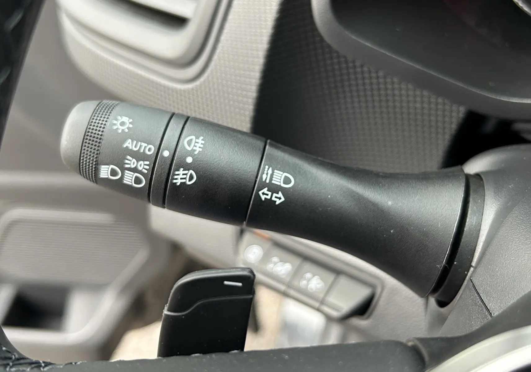 Gros plan sur la commande des feux et clignotants à gauche du volant du Renault Trafic Fourgon gris Comète.