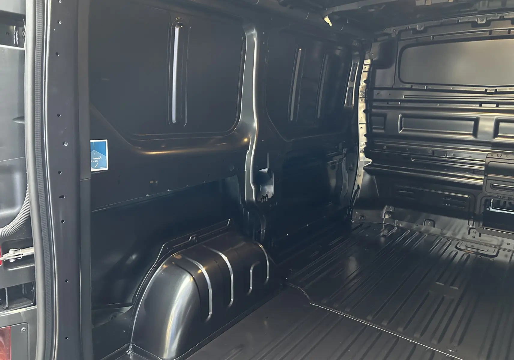 Vue intérieure du compartiment de chargement noir du Renault Trafic Fourgon Advance 3T, montrant la paroi et le plancher métalliques.