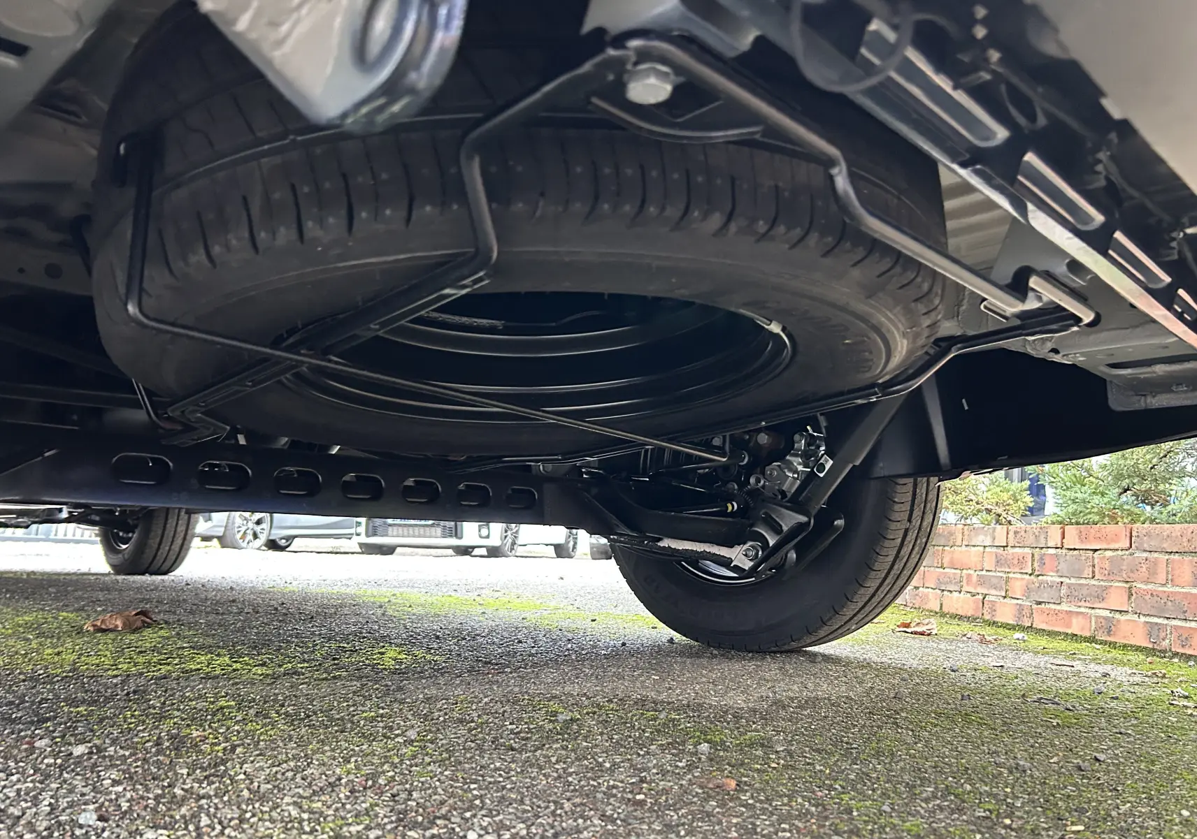 Vue en contre-plongée sous le Renault Trafic Fourgon gris, montrant la roue de secours et le châssis arrière.