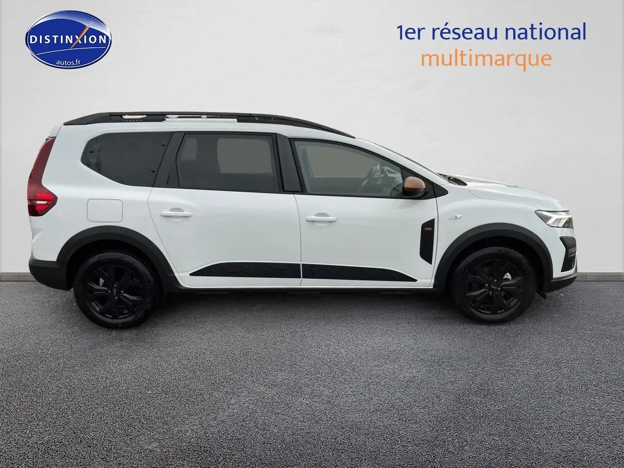 Profil droit d’un Dacia Jogger blanc 2025 avec barres de toit noires et jantes alliage sombres.