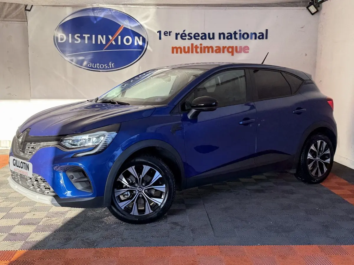 Renault Captur bleu 2024 en vue 3/4 avant droit, avec jantes alliage et phares LED visibles en intérieur showroom.