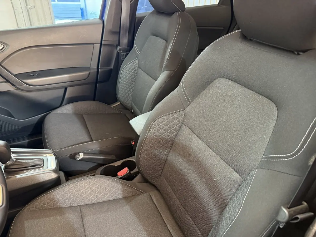 Vue intérieure côté avant droit des sièges tissu gris avec coutures blanches et levier de boîte automatique Renault Captur 2024.