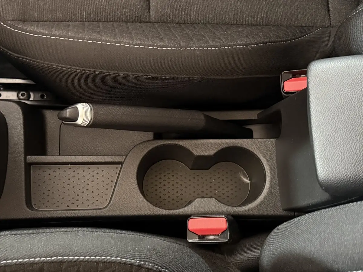 Vue plongeante sur la console centrale noire du Renault Captur 2024 avec frein à main manuel et porte-gobelets.