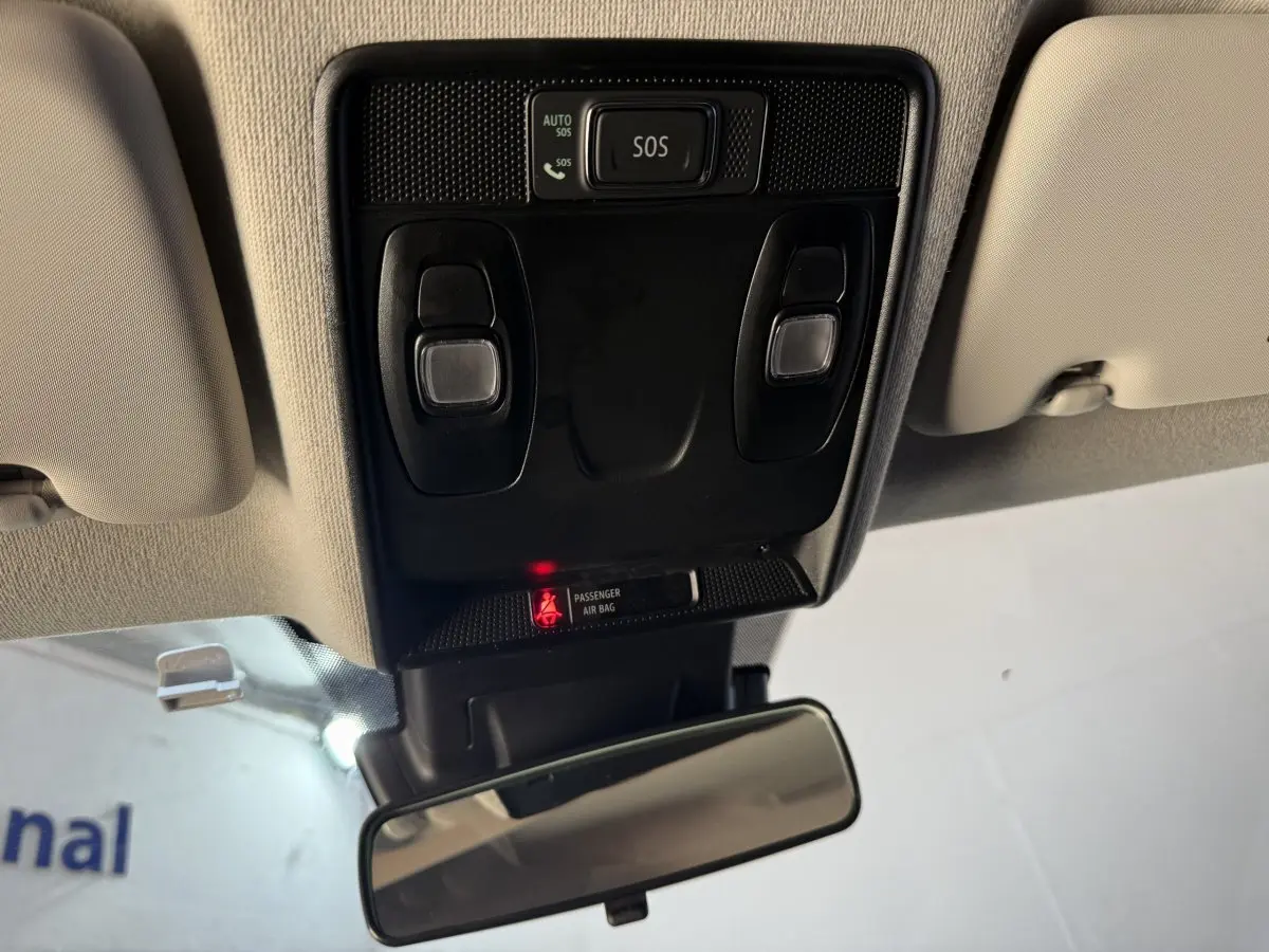 Vue intérieure du plafonnier avec boutons SOS et éclairage, rétroviseur central et plafond beige du Renault Captur bleu 2024.