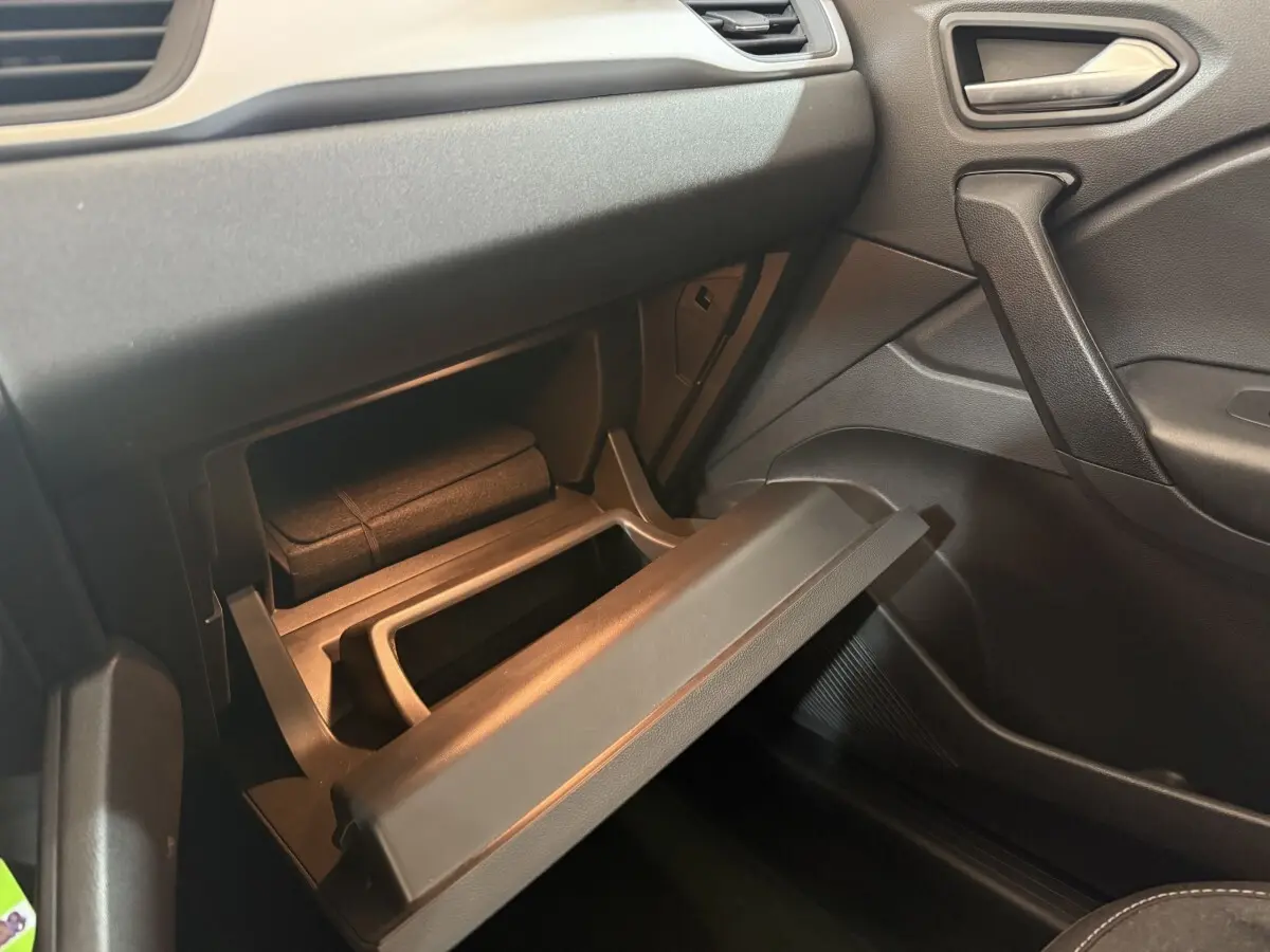 Vue intérieure côté passager du coffre à gants ouvert dans un Renault Captur bleu, version hybride 2024.