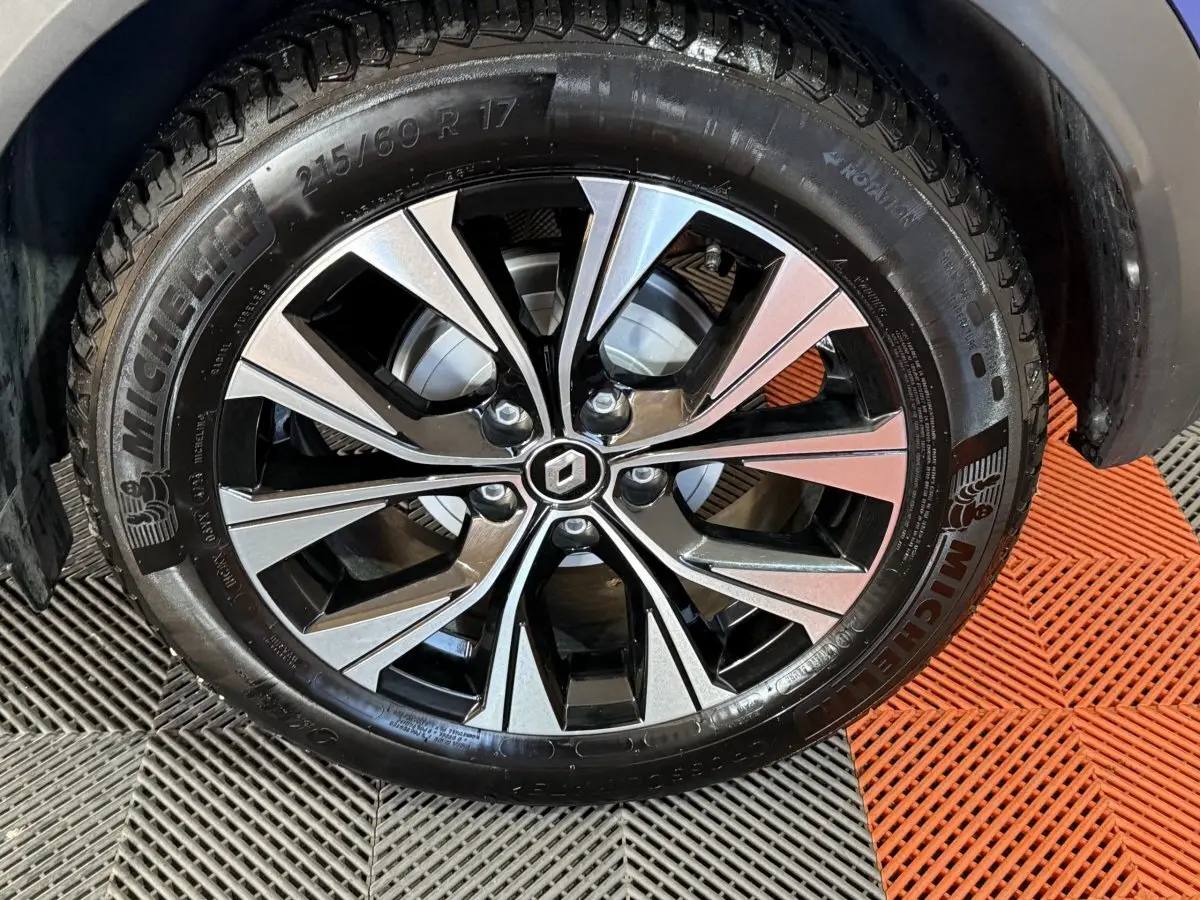 Gros plan sur la roue avant gauche du Renault Captur bleu, jante alliage bicolore avec logo Renault central.