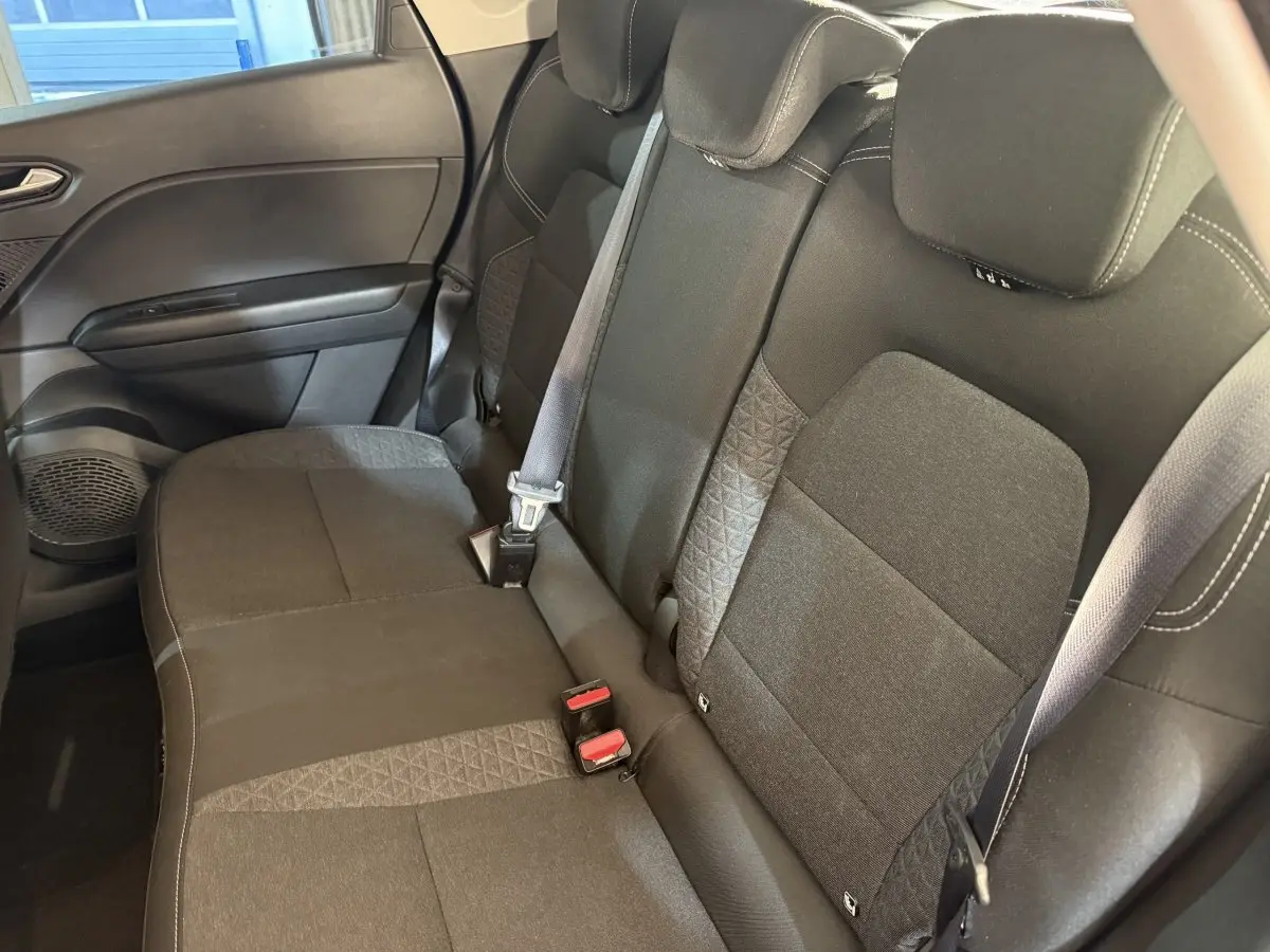Vue intérieure côté droit montrant la banquette arrière noire du Renault Captur 2024 avec ceintures de sécurité visibles.