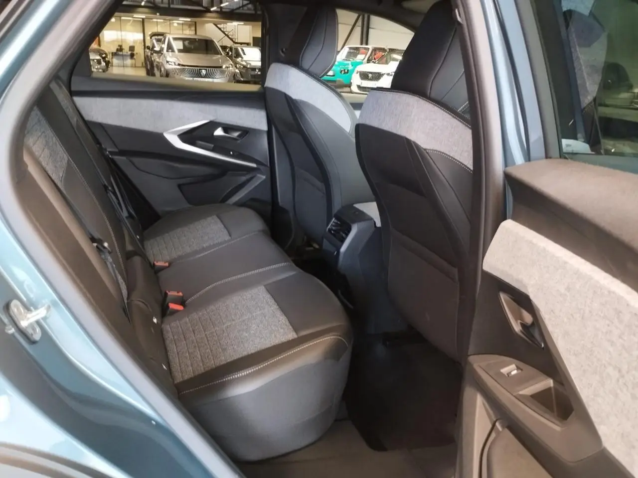 Vue côté gauche arrière de l’habitacle du Peugeot 3008 bleu Azul, sièges tissu gris et noir avec surpiqûres claires.