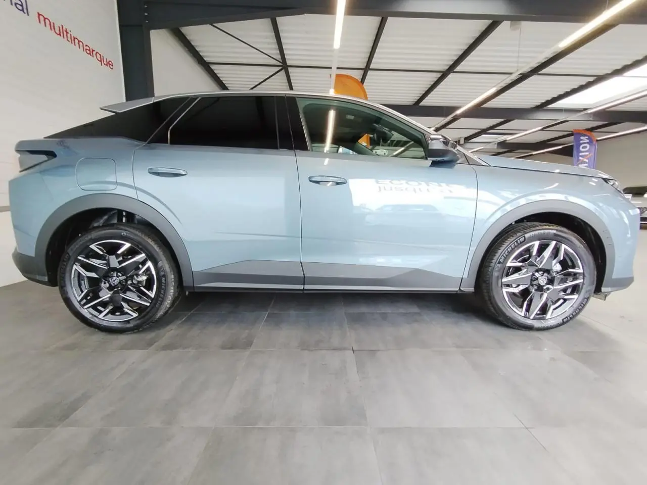 Profil côté gauche du Peugeot 3008 hybride 2025 en bleu métallisé avec jantes alliage noires diamantées.