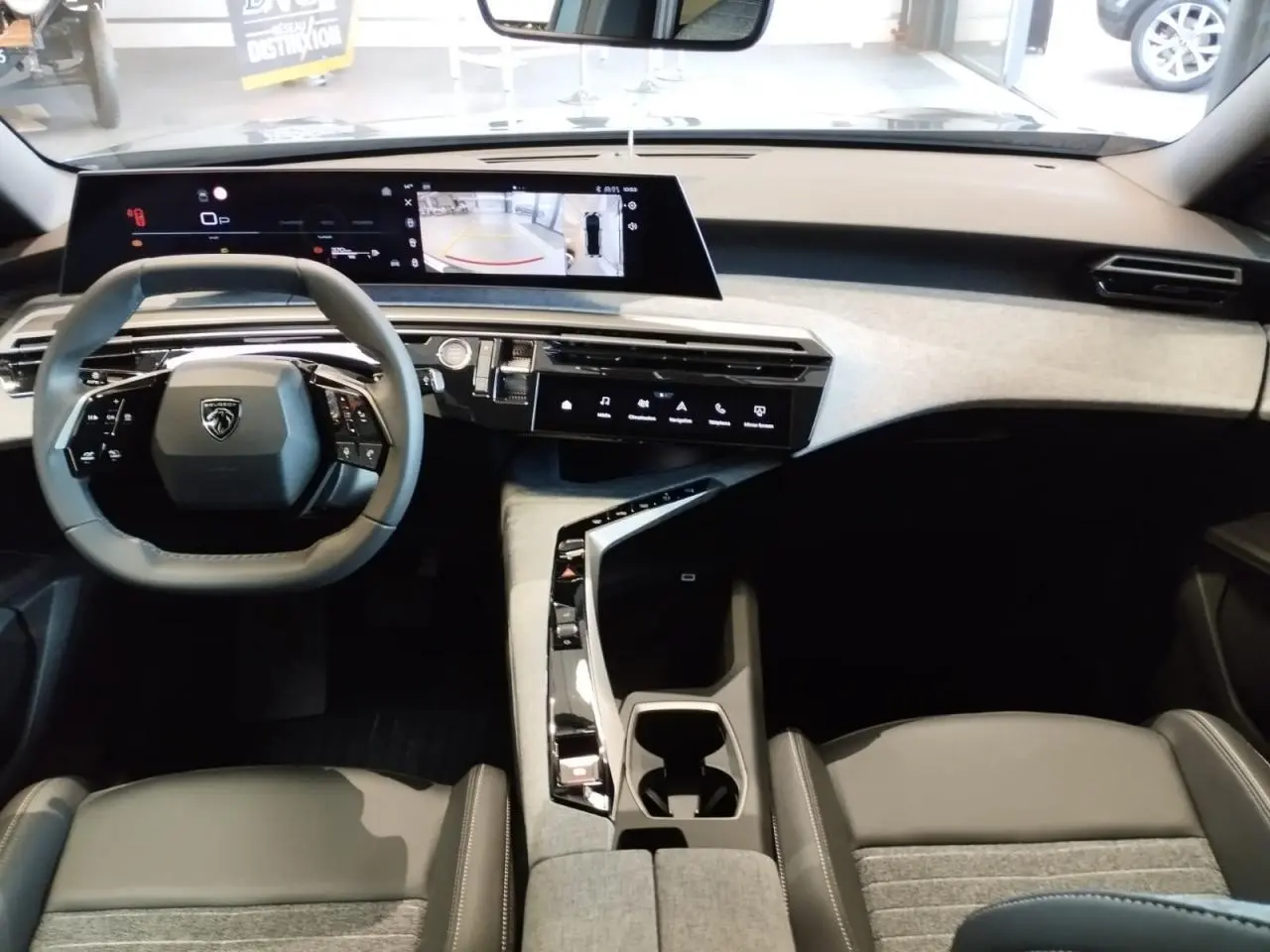 Vue intérieure avant du Peugeot 3008 2025, tableau de bord avec double écran incurvé et volant compact noir.