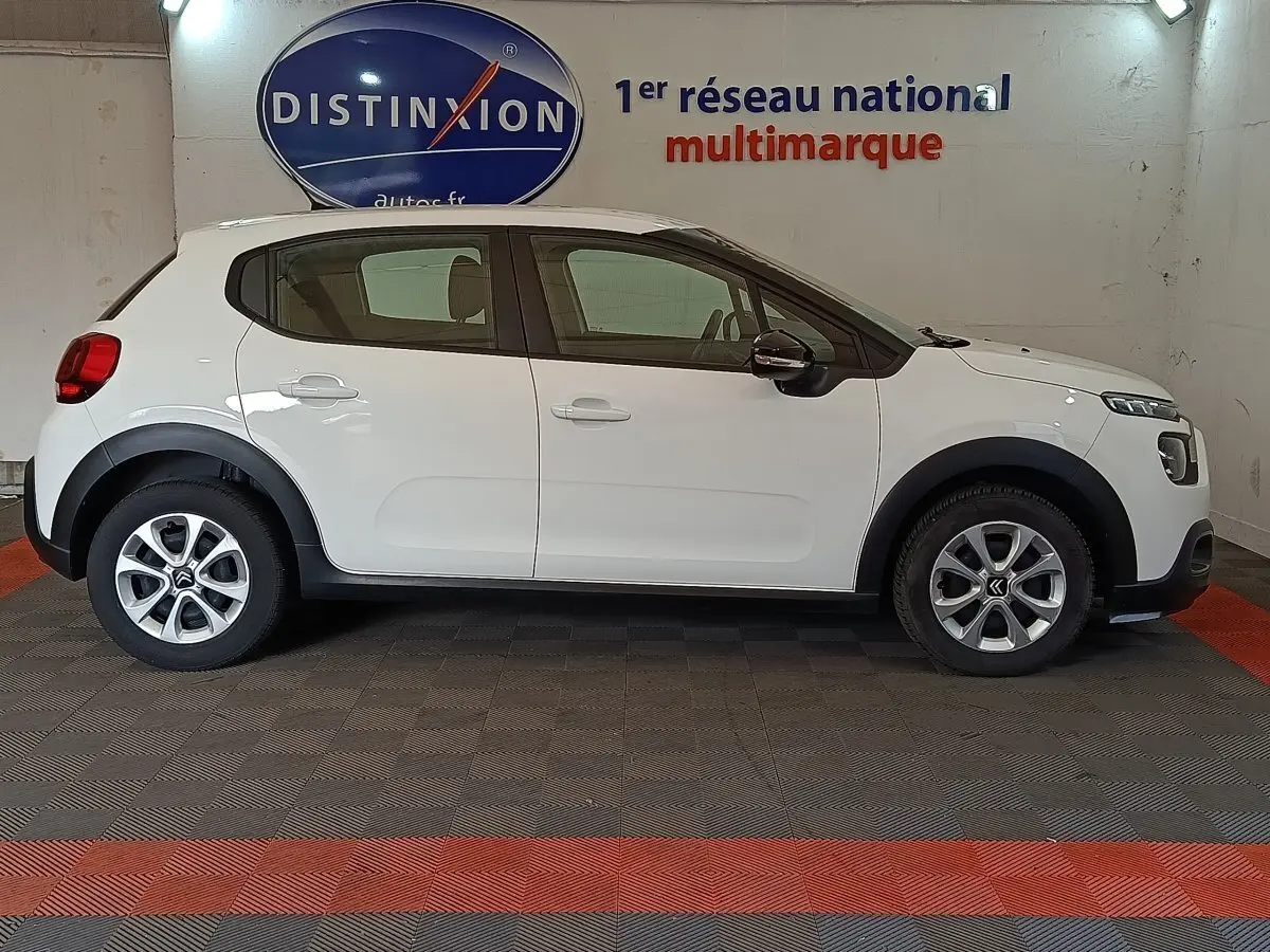 Profil côté gauche d'une Citroën C3 blanche 2020 avec jantes alliage et protections noires sur les passages de roues.