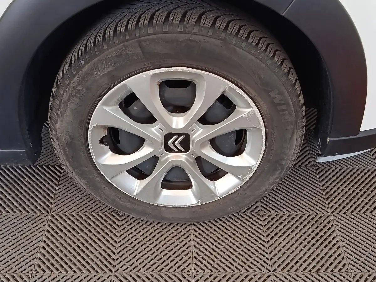 Gros plan sur la roue avant gauche d'une Citroën C3 blanche de 2020 avec jante alliage et logo Citroën central.