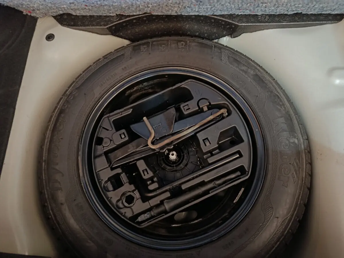 Vue rapprochée de la roue de secours et des outils de bord dans le coffre d'une Citroën C3 blanche de 2020.