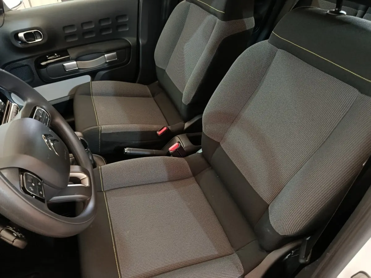 Vue intérieure côté conducteur de la Citroën C3 2020, sièges tissu gris avec surpiqûres jaunes et volant multifonction.