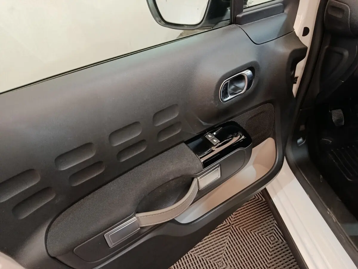 Vue rapprochée de la porte avant gauche intérieure noire et blanche de la Citroën C3 PureTech 2020.