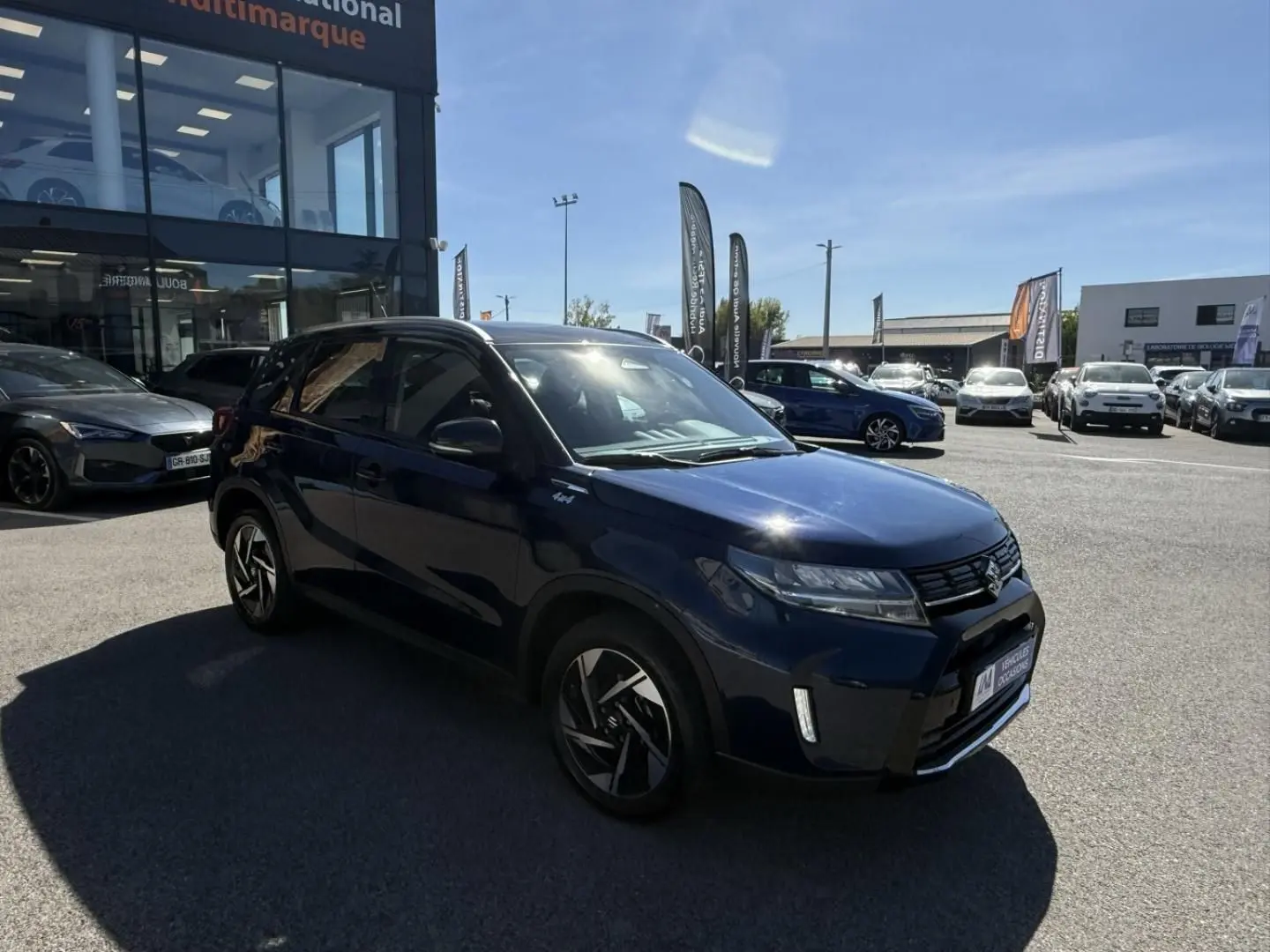 Suzuki Vitara 2025 bleu foncé métal en 3/4 avant droit, avec jantes alliage et badge Allgrip visible sur l'aile.