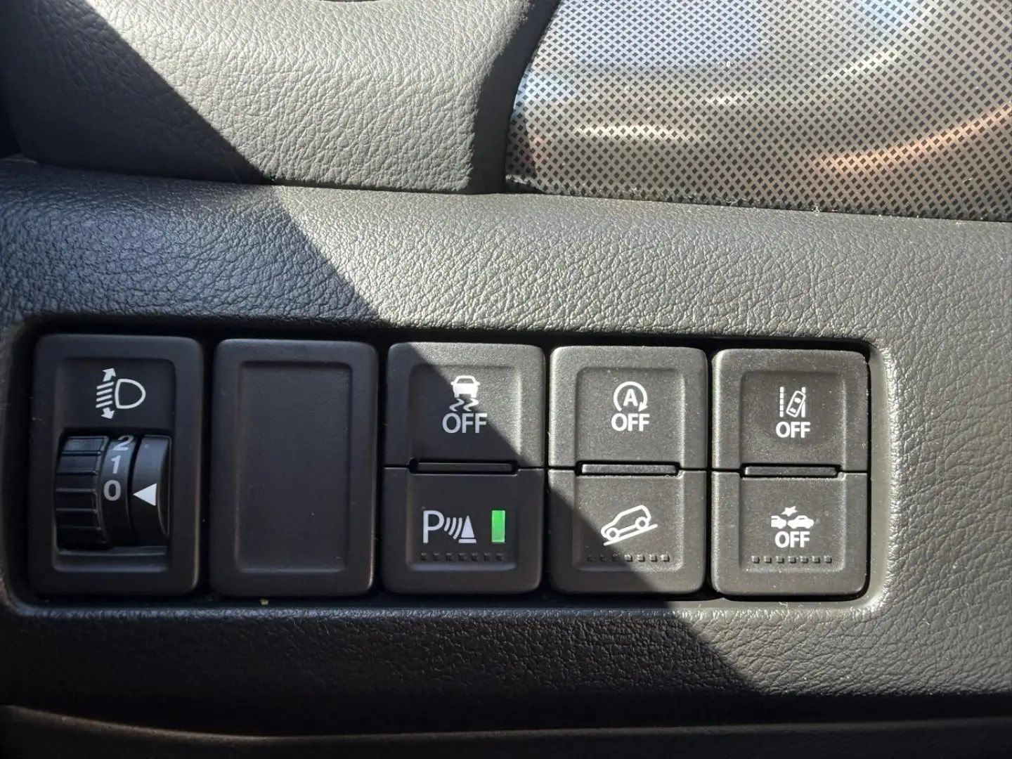 Gros plan sur les commandes de sécurité et assistance du tableau de bord du Suzuki Vitara 2025, intérieur noir texturé.