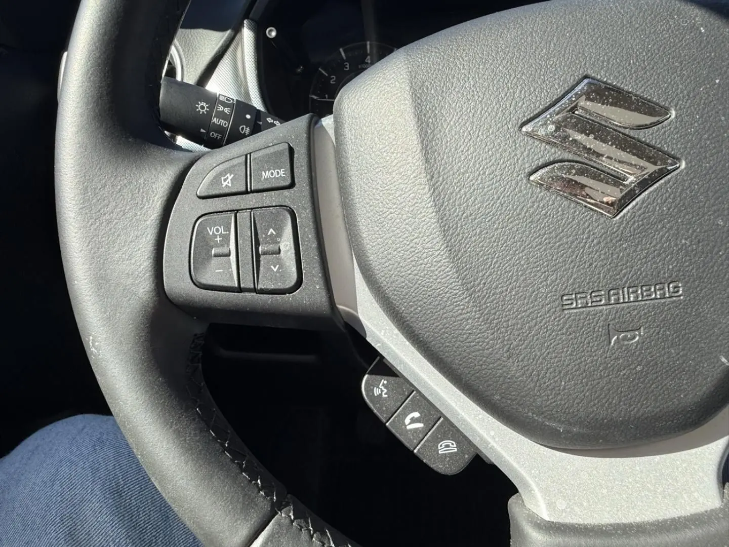 Vue rapprochée du volant noir du Suzuki Vitara 2025, avec commandes audio et logo Suzuki argenté visible.