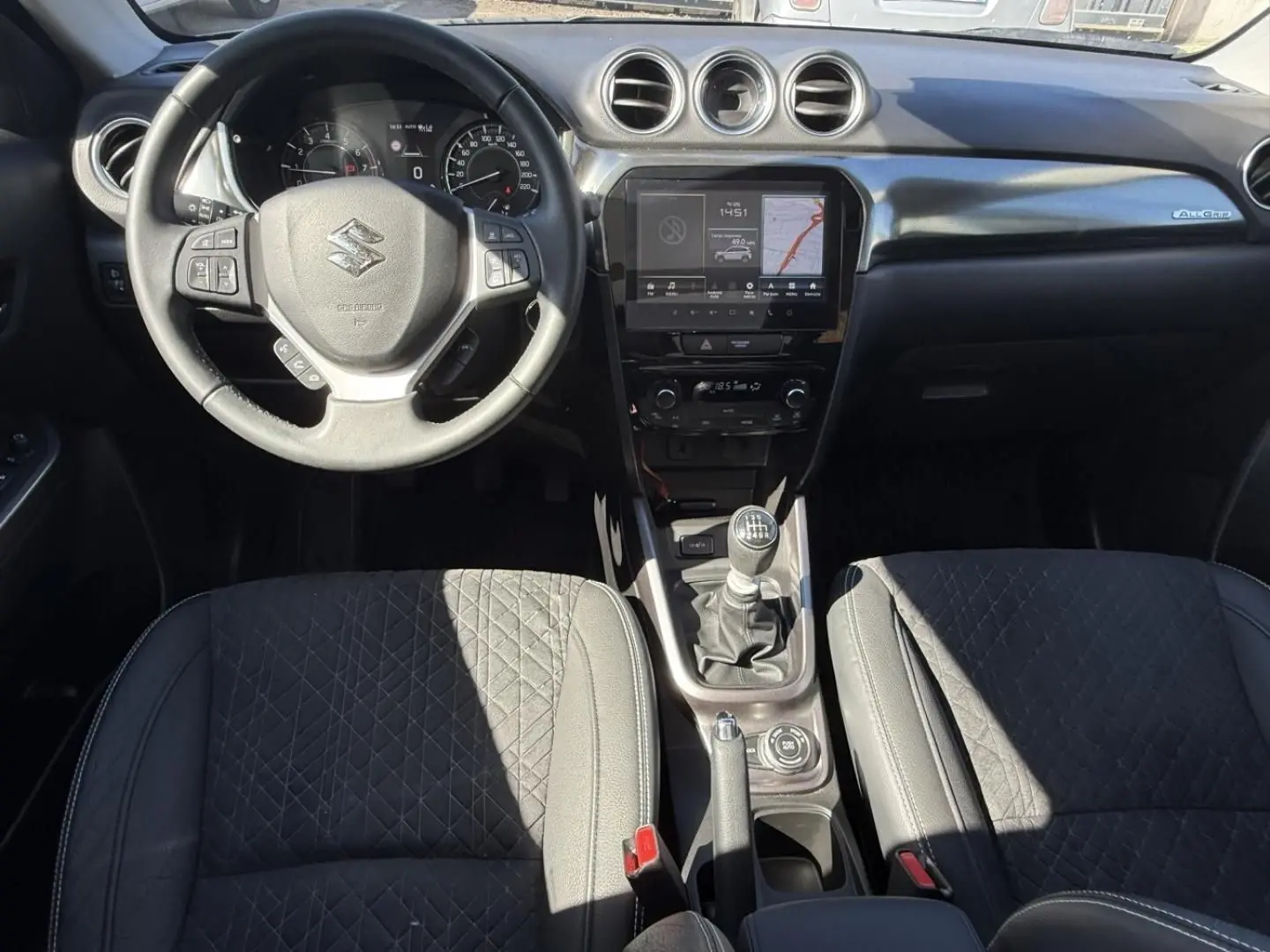 Vue intérieure avant du Suzuki Vitara 2025 bleu foncé, volant multifonction, boîte manuelle et écran tactile central.