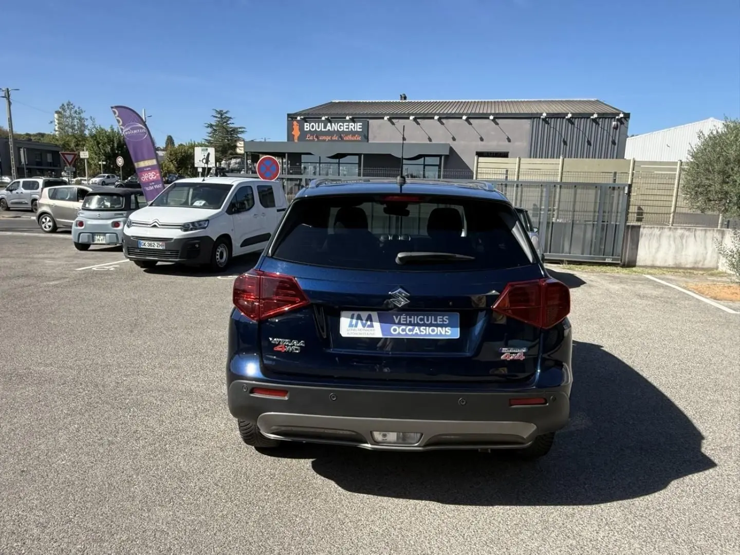 Vue arrière d’un Suzuki Vitara bleu foncé métal 2025 avec badges Allgrip et 4WD sur un parking extérieur.