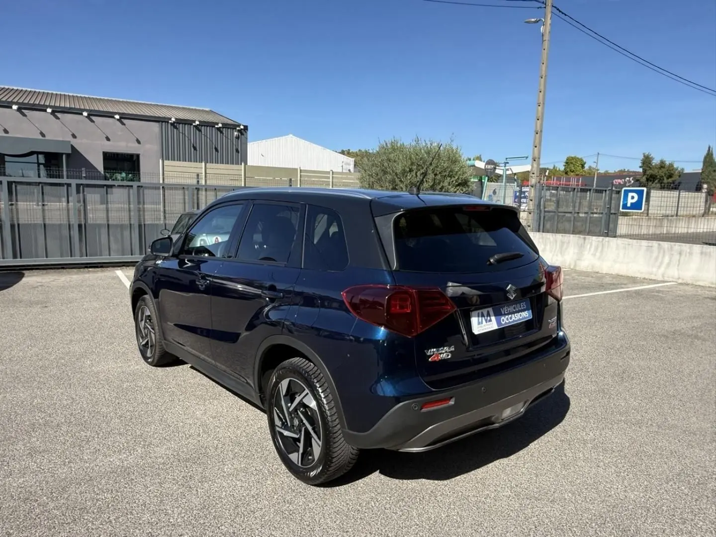 Suzuki Vitara 2025 bleu foncé métal en 3/4 arrière droit, avec jantes alliage et toit noir contrasté.