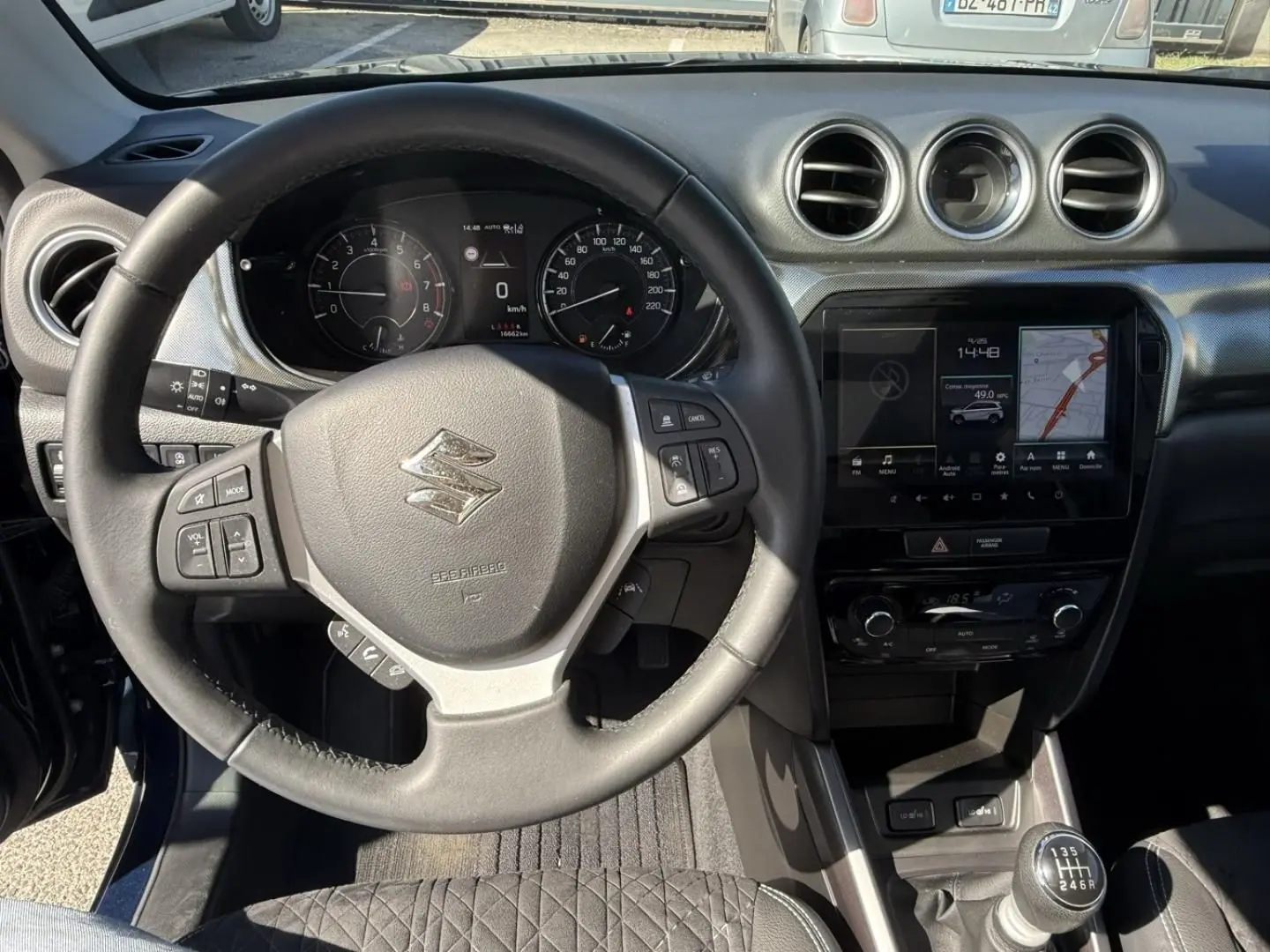 Vue intérieure centrée sur le volant et la console centrale du Suzuki Vitara 2025, avec boîte manuelle et écran tactile.