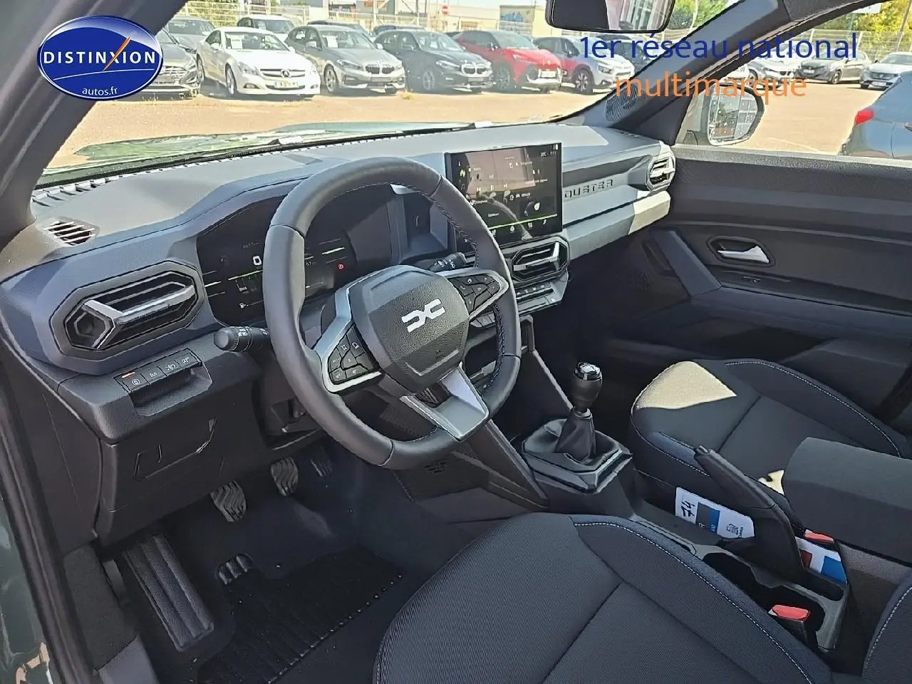 Intérieur avant du Dacia Duster 2025 vert kaki, vue côté conducteur avec volant multifonction et écran tactile.