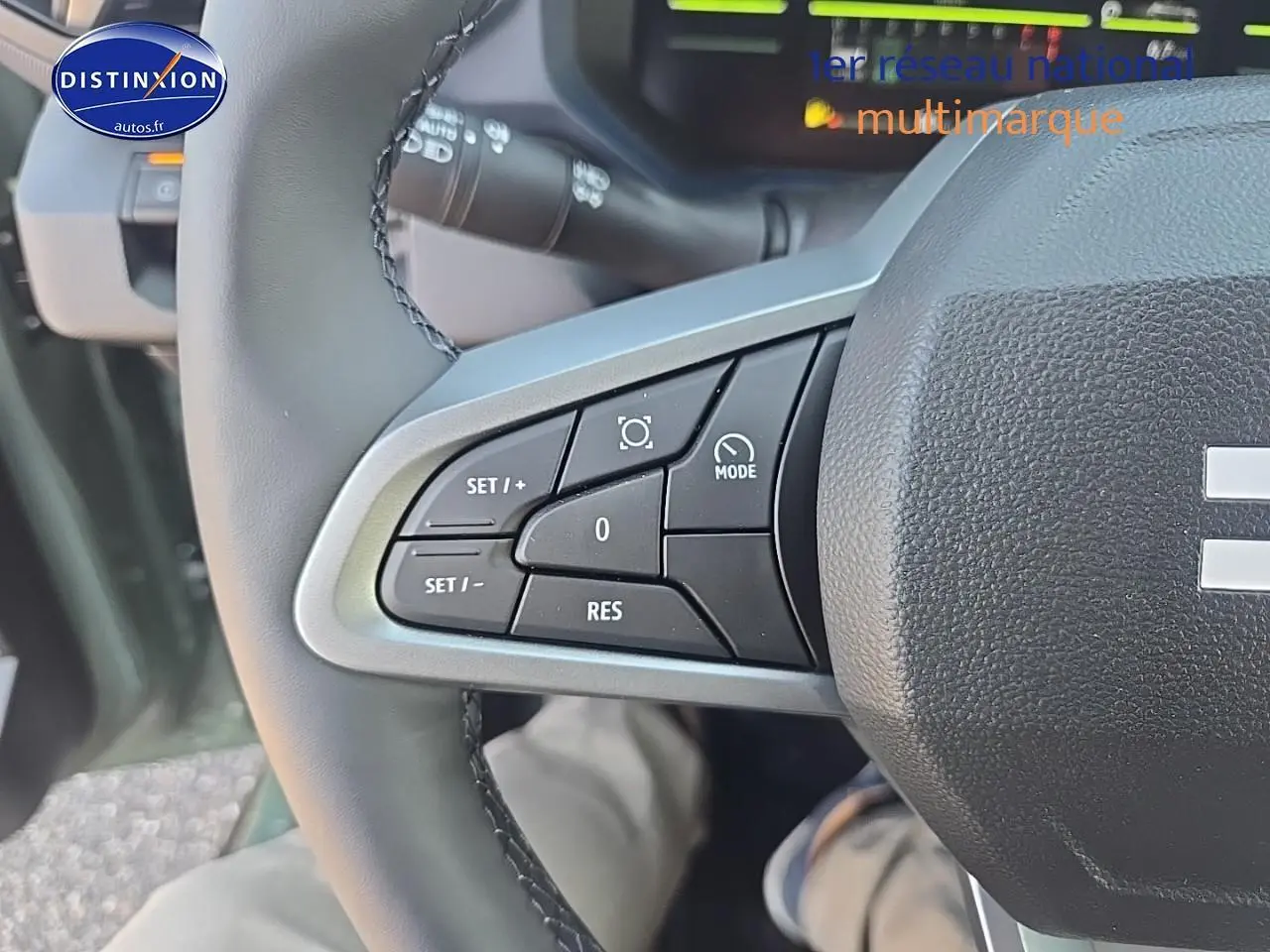 Gros plan sur les commandes à gauche du volant du Dacia Duster vert kaki 2025, avec boutons multifonctions visibles.