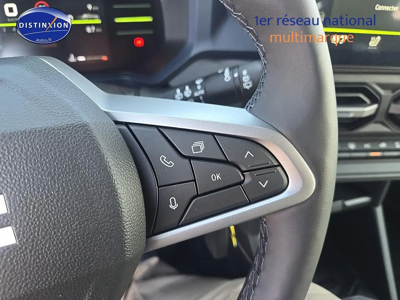 Gros plan sur les commandes multifonctions à droite du volant du Dacia Duster vert kaki 2025, avec tableau de bord en arrière-plan.